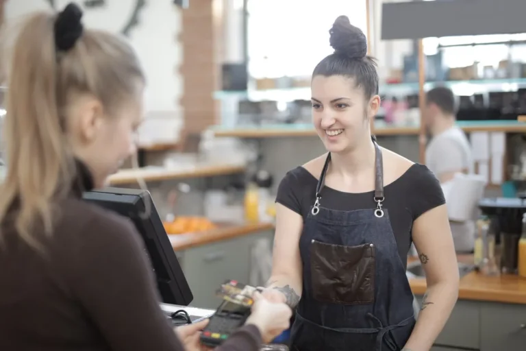 Barista taking a card payment at the POS counter of a small café