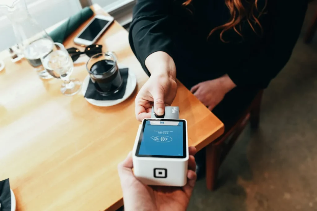 Square card reader being used for contactless payment at a restaurant table